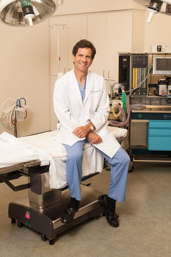 Dr. Knowling in his labcoat sitting on a surgical bed