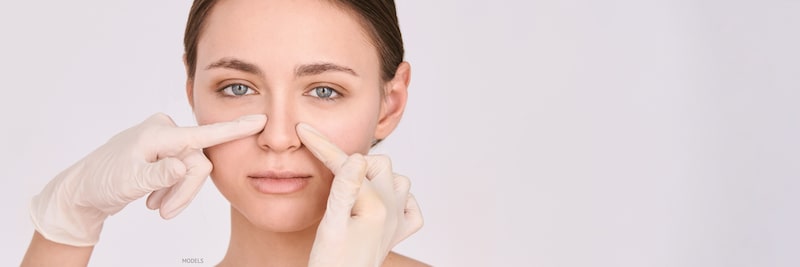 Woman having the sides of her nose pressed on by a doctor